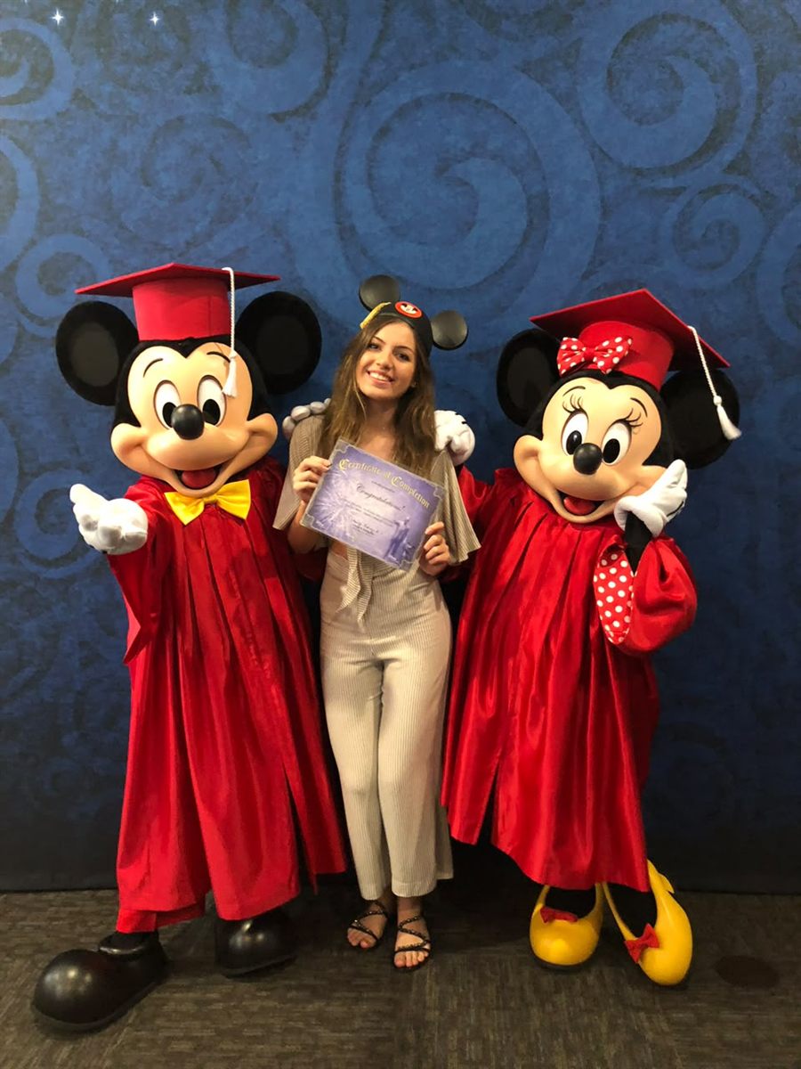 Giovanna com Mickey e Minnie, segurando o certificado de conclusão na Disney